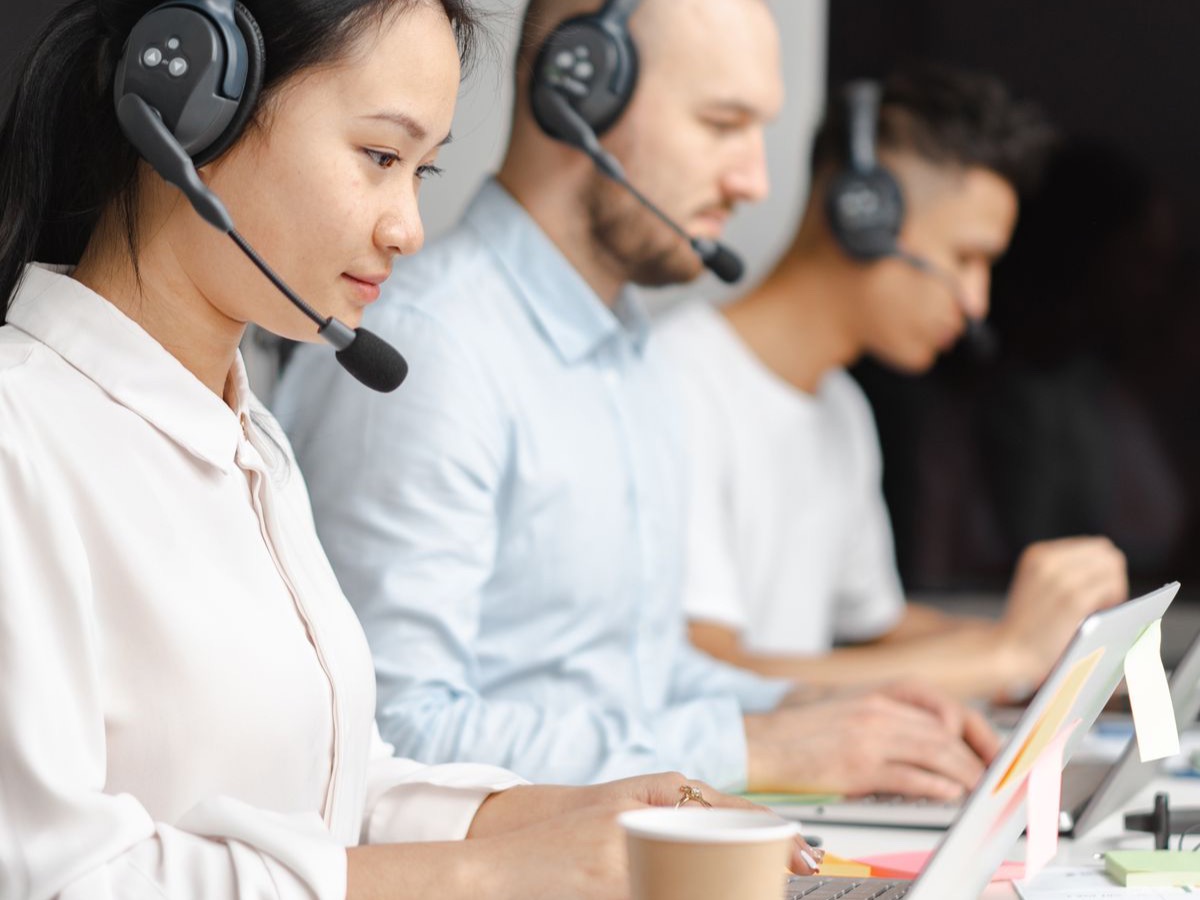 Row of customer service agents wearing headsets at their workstations
